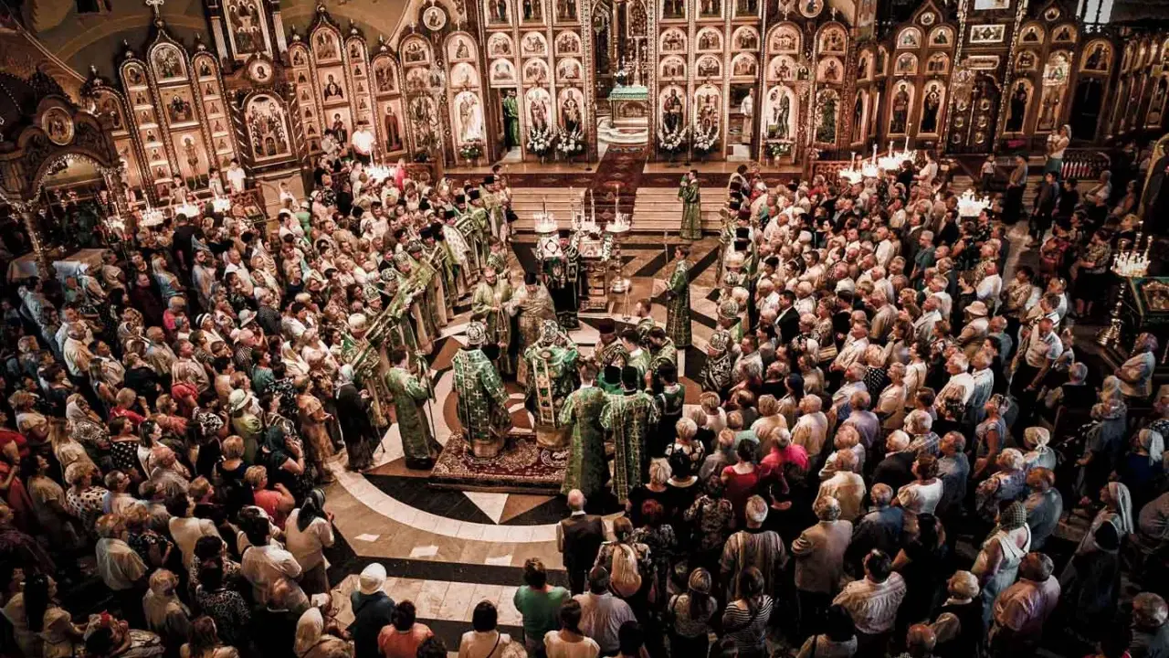 Uroczysta liturgia w największej cerkwi w Polsce. Wierni zgromadzeni wokół ikonostasu, duchowieństwo w bogatych szatach.
