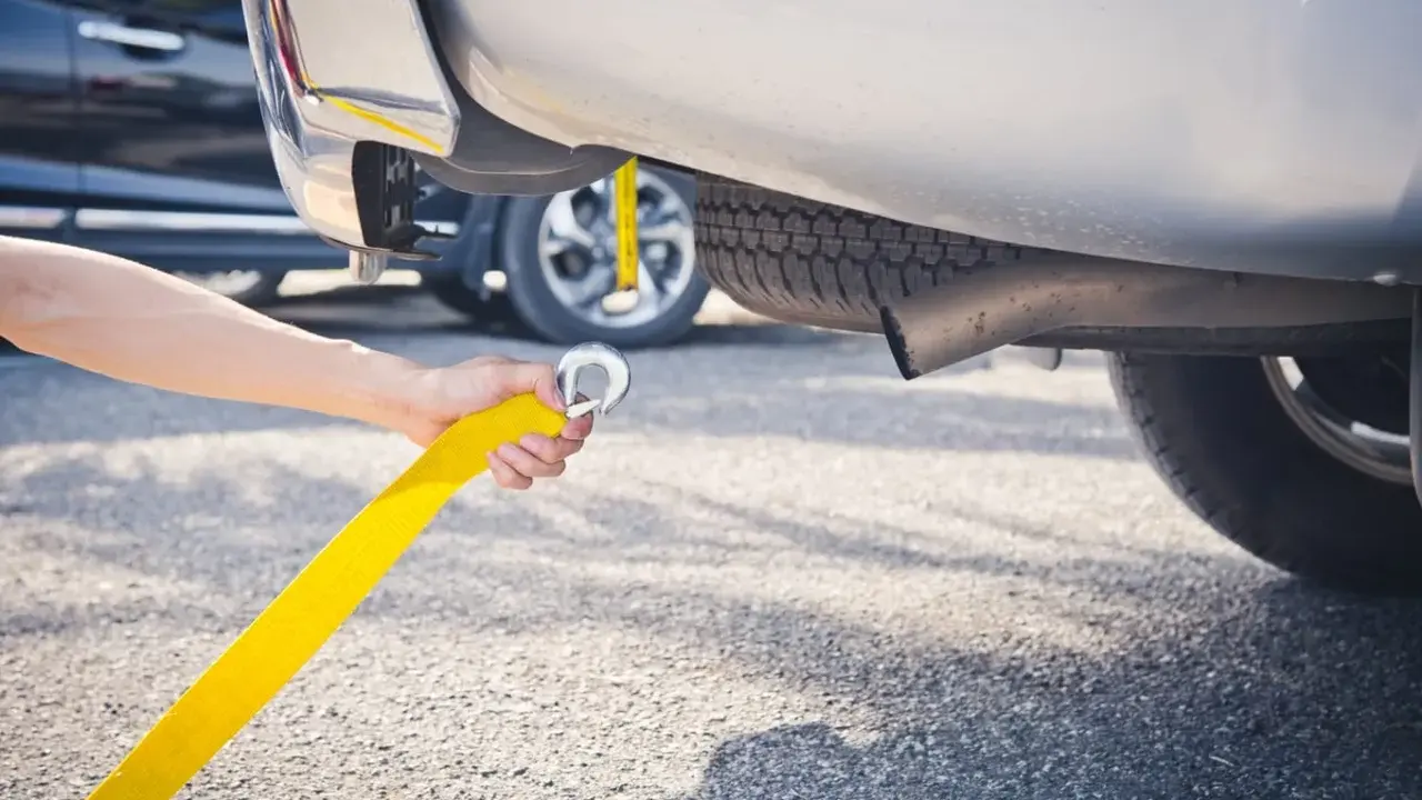 Ręka trzymająca żółtą linę do holowania, przygotowująca do holowania na autostradzie.