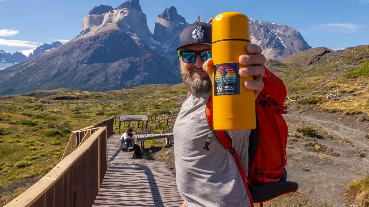 Mężczyzna z żółtym termosem na tle majestatycznych gór. To z pewnością Patagonia, a nie Alzacja.