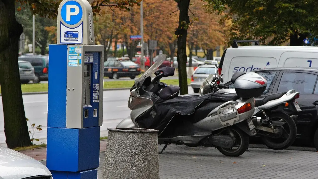 Parkomat z symbolem "P" i skuterem obok. Upewnij się, że masz ważny bilet, by uniknąć mandatu za parkowanie.