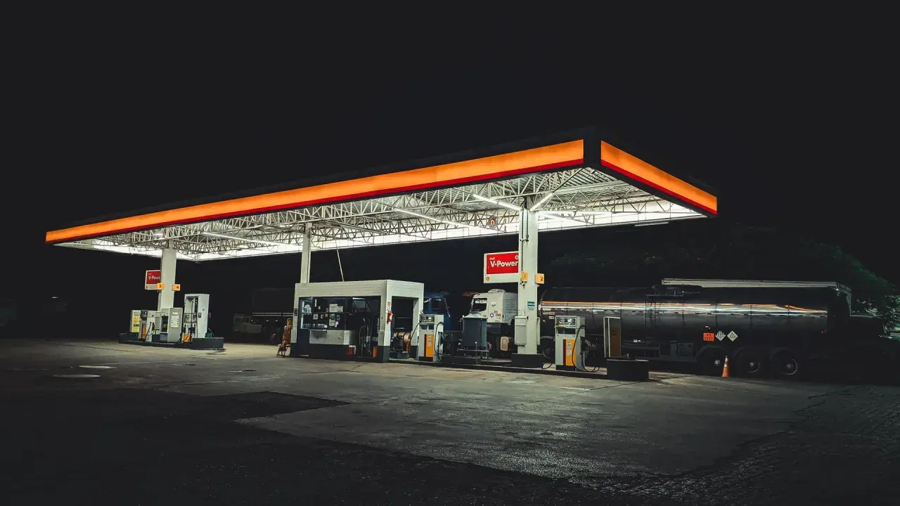Nocna stacja paliw w Polsce, oświetlona neonami, z dystrybutorami i cysterną.