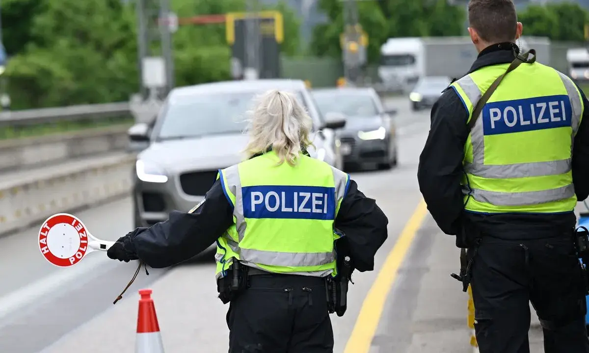Policjanci kierują ruchem na trasie w Zgorzelcu. Jeden z nich trzyma znak "STOP".