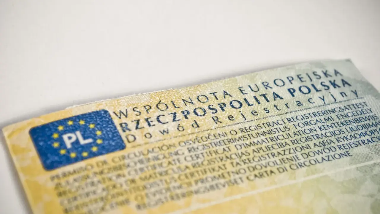 Dowód rejestracyjny pojazdu, niezbędny do ubezpieczenia auta, z flagą PL i tekstem w wielu językach.