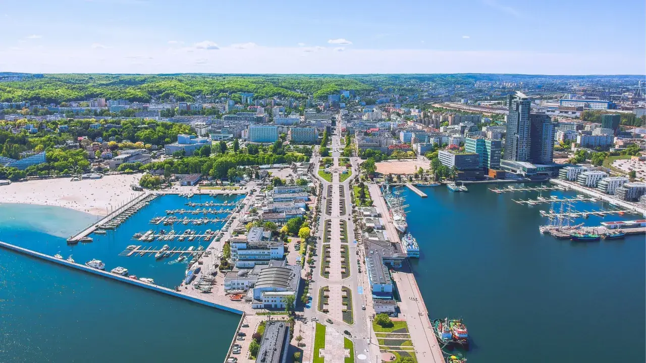 Widok na Gdynię z lotu ptaka. Widać port jachtowy, plażę i zabudowę miejską. Odległość do Wejherowa jest spora, ale widok zapiera dech.
