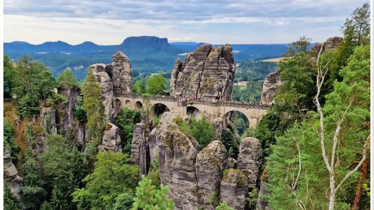 Kamienny most Basteibrücke w Szwajcarskiej Saksonii, łączący skalne baszty pośród zielonych lasów i gór.