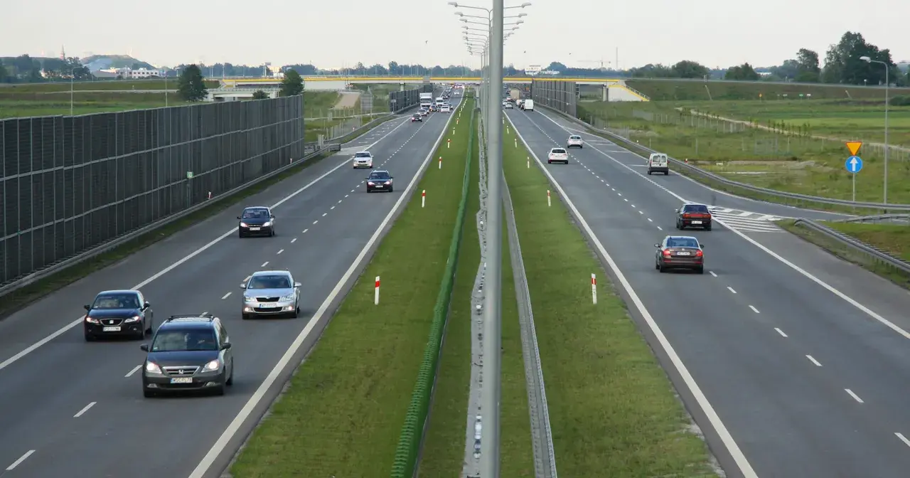 Różne rodzaje dróg: autostrada z pasami ruchu, barierkami i ekranami akustycznymi. Samochody poruszają się po jezdni.