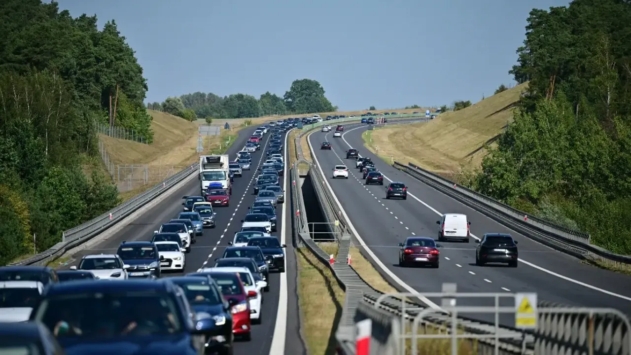 Korek samochodów na autostradzie A1, zieleń po bokach, błękitne niebo.