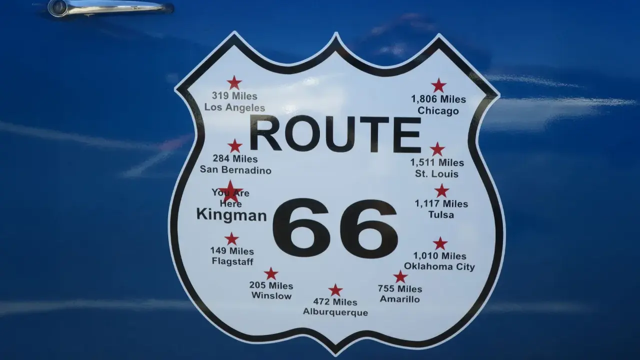 Tablica z napisem "ROUTE 66" i odległościami do miast, w tym "You Are Here Kingman".