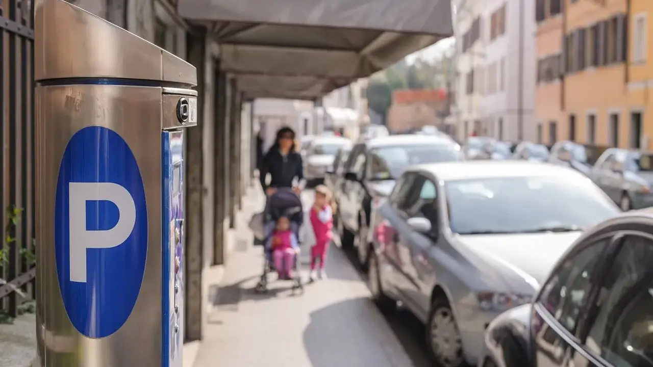 Parkomat z symbolem "P" i w tle kobieta z dziećmi na wózku, a obok samochody. Czy to parkowanie w miejscu niedozwolonym?