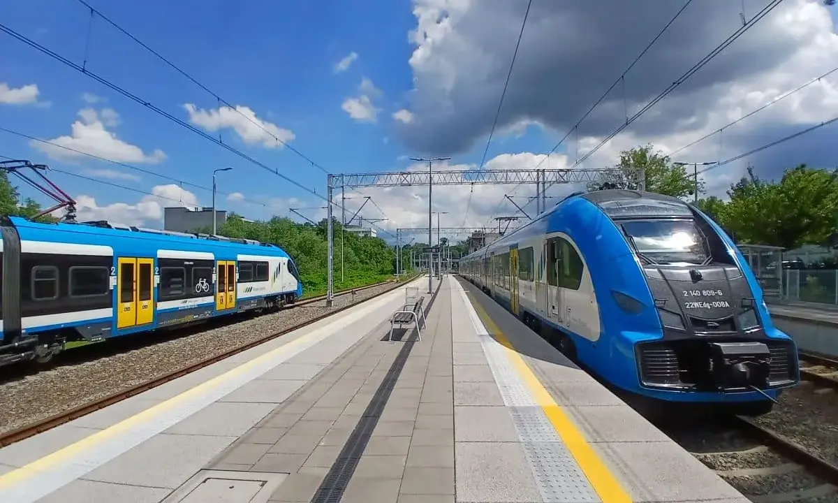 Dwa niebiesko-białe pociągi stoją na stacji, gotowe do podróży. Może to najszybsza trasa do Kielc?