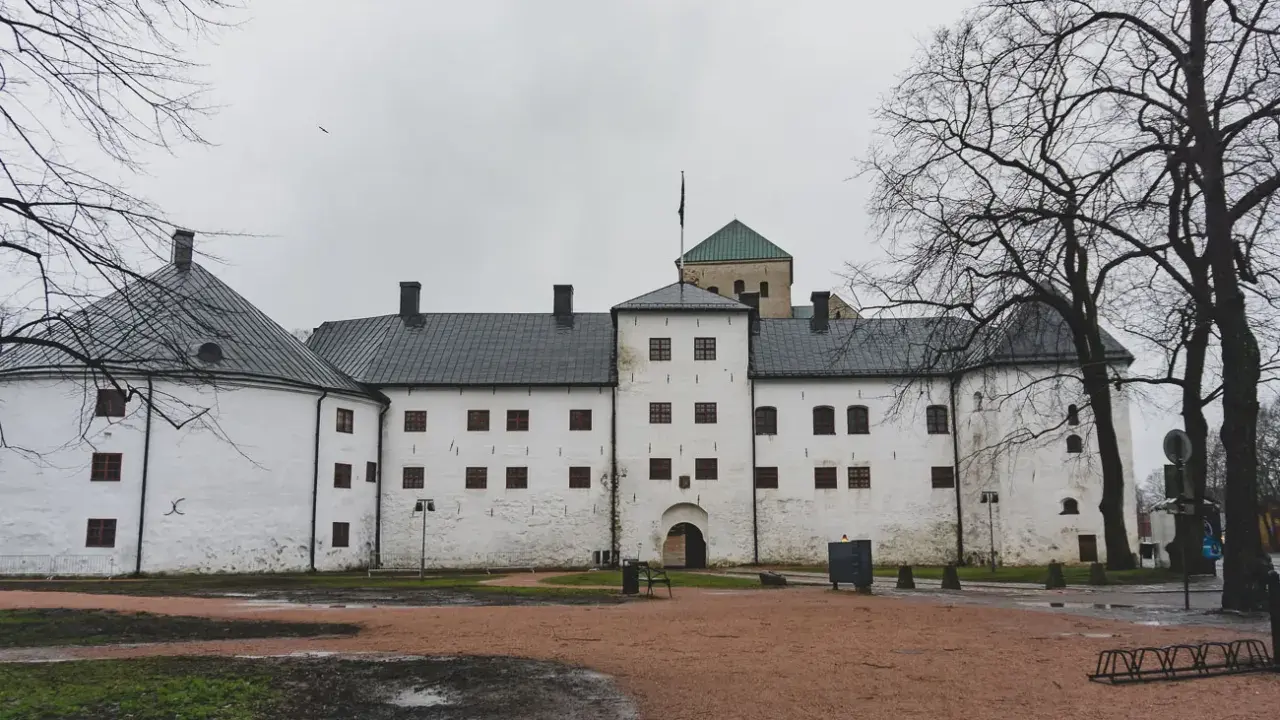 Biały zamek z wieżą i zielonym dachem, symbol najstarszego miasta w Finlandii.