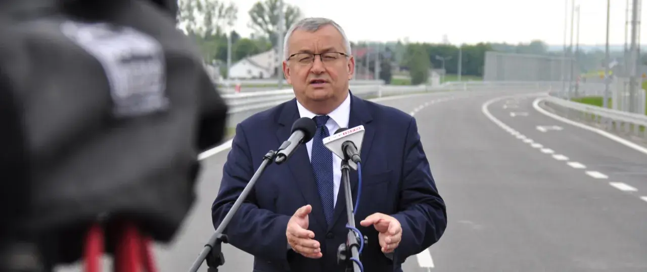 Mężczyzna w garniturze przemawia do mikrofonów na tle nowej drogi, która połączy Lublin i Rzeszów.