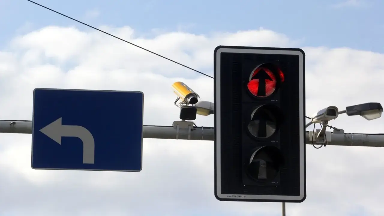 Fotoradar na światłach, czerwone światło dla kierunku na wprost. Obok znak nakazu skrętu w lewo.