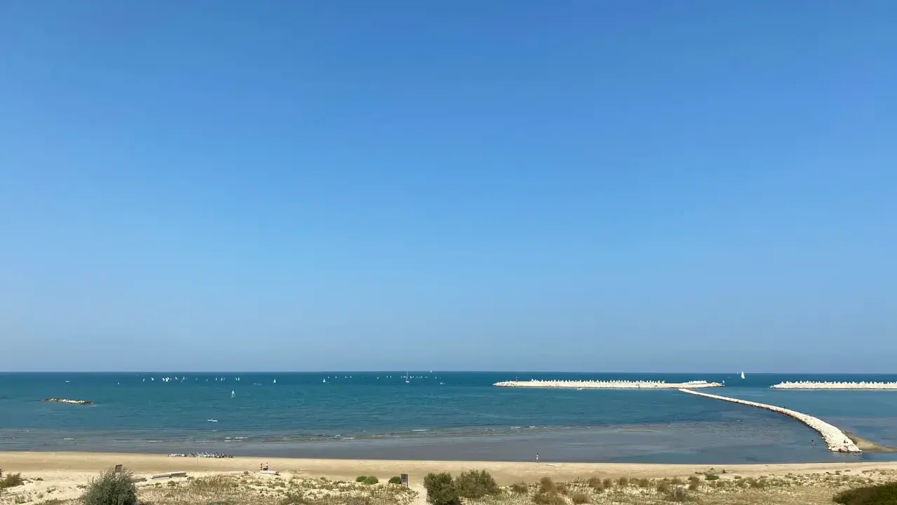 Piękny dzień nad morzem w Pescara i okolice. Wiele żaglówek na turkusowej wodzie, piaszczysta plaża i falochrony.