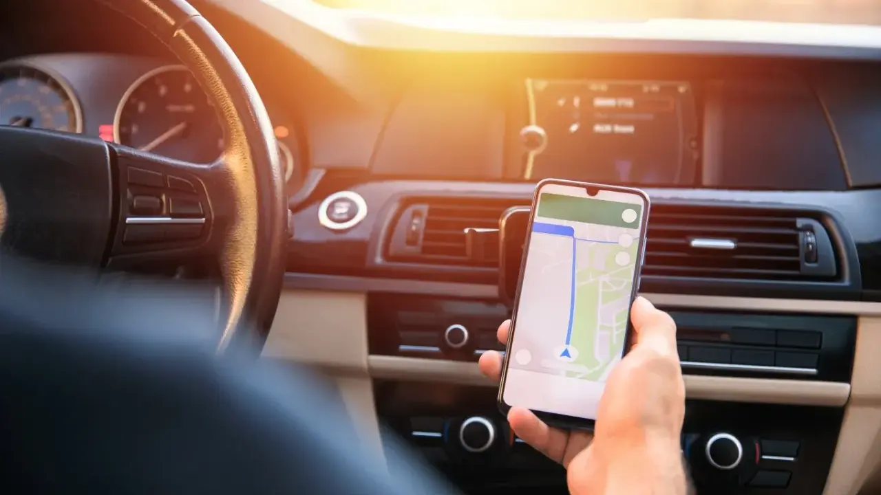 Kierowca używa nawigacji na telefonie. Zastanawia się, ile punktów karnych za telefon grozi za takie zachowanie.