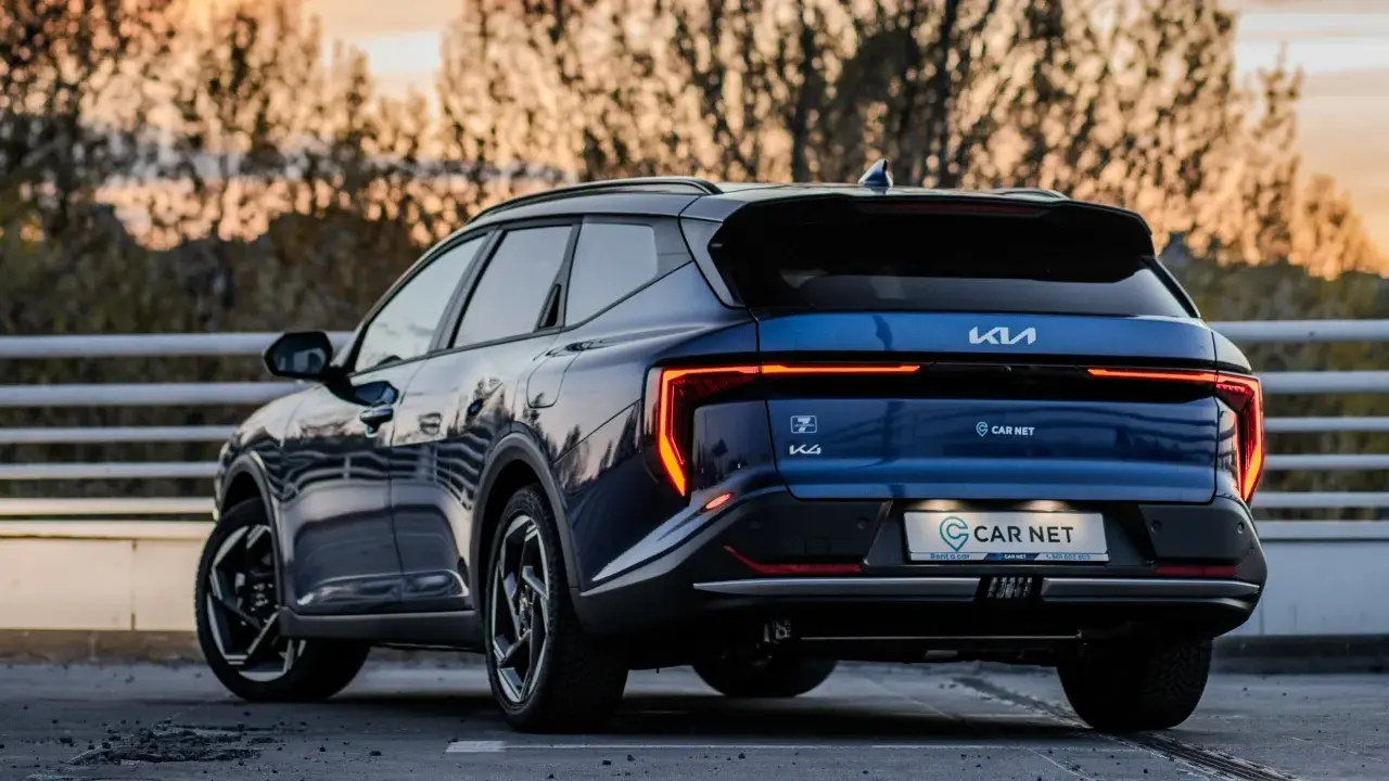 Niebieskie Kia EV6 gotowe na podróż z Poznania do Jeleniej Góry. Zachód słońca nad drzewami.