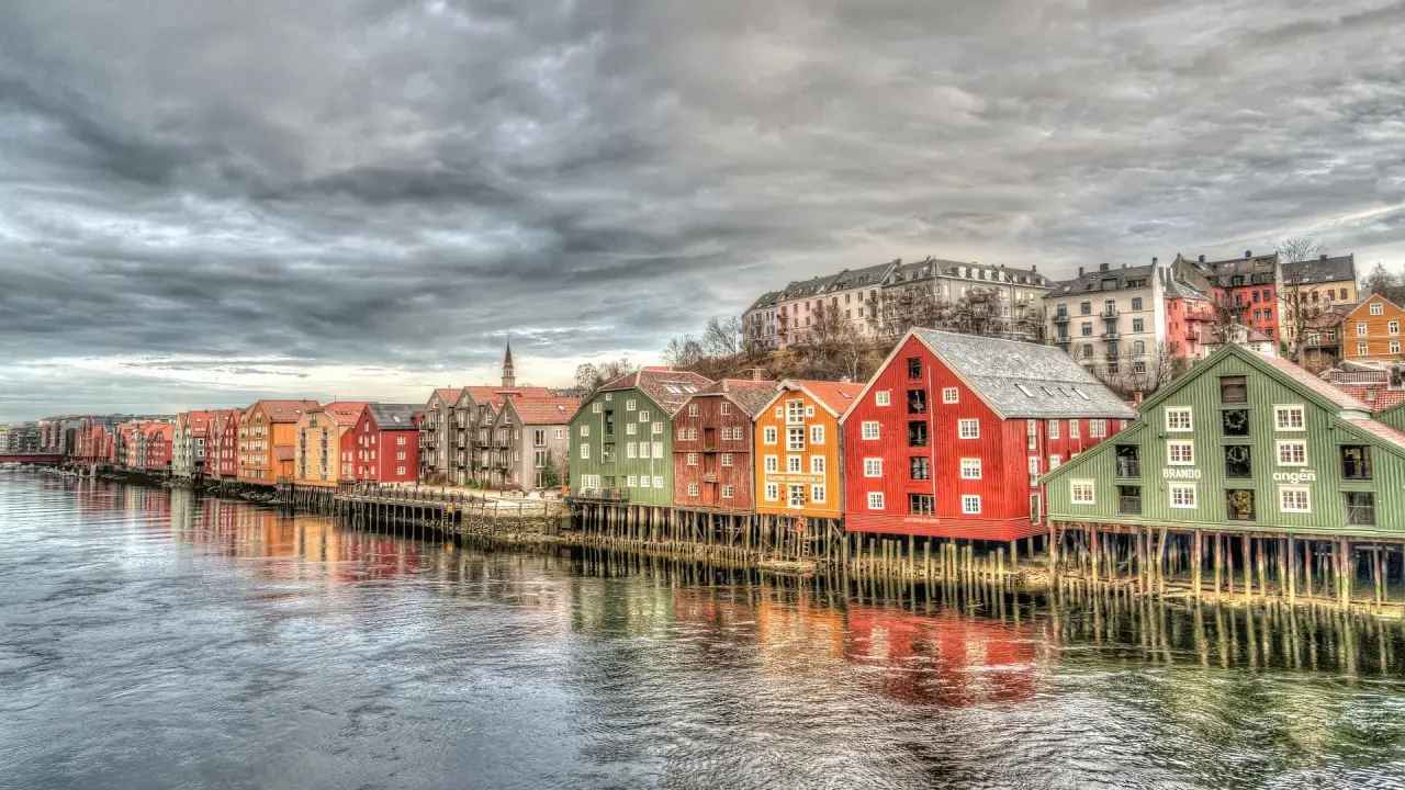 Kolorowe domy na palach wzdłuż rzeki, przypominające malownicze trondheim fiordy.