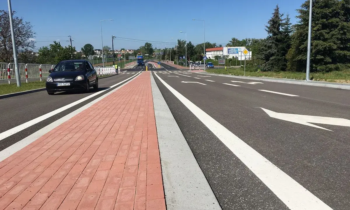 Nowy chodnik i droga rowerowa w mieście na trasie Gostyń-Kórnik. Czarny samochód jedzie po jezdni.