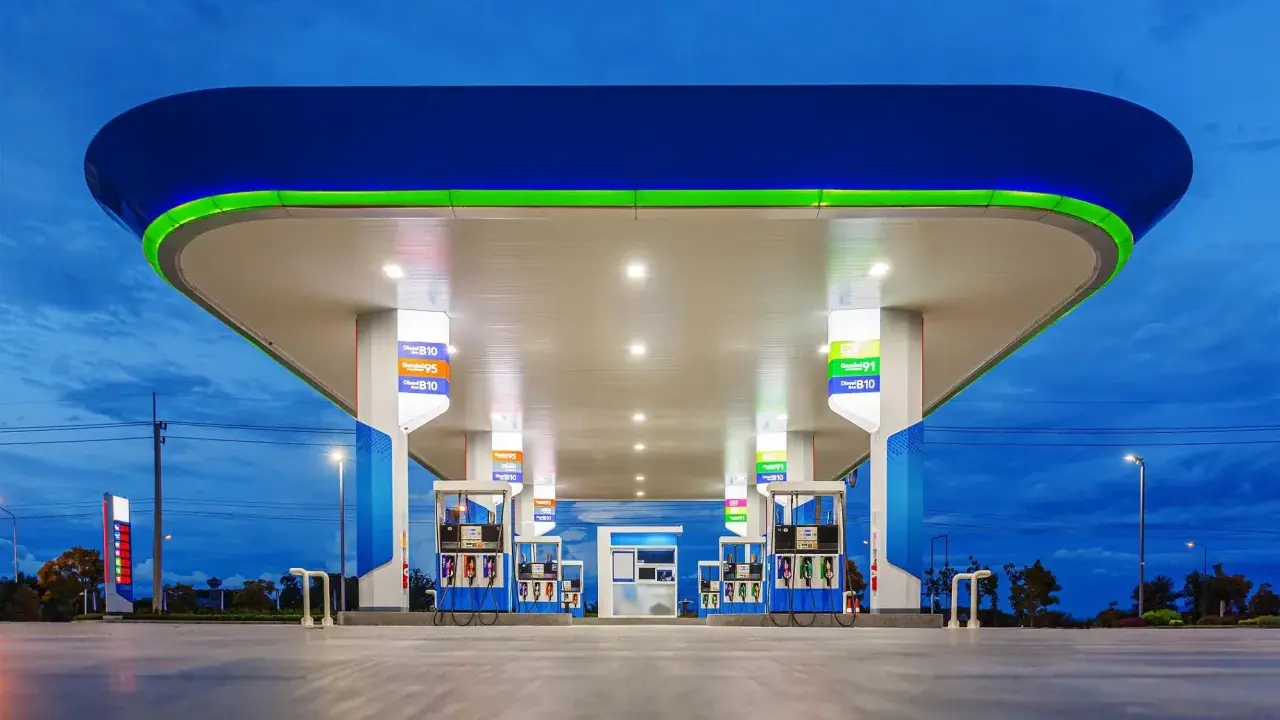 Stacja paliw z podświetlanym zadaszeniem i dystrybutorami. Widoczne ceny paliw, np. Diesel B10, Gasohol 95, E20.