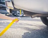 Ręka trzymająca żółtą linę do holowania, przygotowująca do holowania na autostradzie.