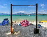 Słoneczne plaże nad jeziorem Garda, z parasolami, leżakami i wodnymi atrakcjami w tle.