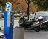 Parkomat z symbolem "P" i skuterem obok. Upewnij się, że masz ważny bilet, by uniknąć mandatu za parkowanie.
