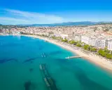 Widok z lotu ptaka na Lazurowe Wybrzeże Francja: turkusowe morze, piaszczysta plaża, palmy i białe budynki miasta.
