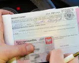 Ręka trzyma mandat karny na kwotę 300 zł. Obok dowód osobisty. Jak uniknąć mandatu? Uważaj na drodze!
