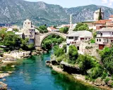 Mostar, Bośnia i Hercegowina: zielona karta dla turystów. Stary Most i rzeka Neretwa w letnim słońcu.