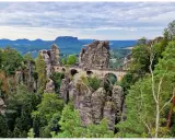Kamienny most Basteibrücke w Szwajcarskiej Saksonii, łączący skalne baszty pośród zielonych lasów i gór.
