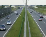 Różne rodzaje dróg: autostrada z pasami ruchu, barierkami i ekranami akustycznymi. Samochody poruszają się po jezdni.