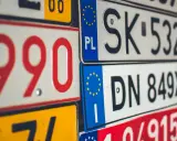 Stos tablic rejestracyjnych, w tym polskie z symbolem PL i europejską gwiazdką. Widać numery takie jak 990, SK 532HH, DN 849XJ.