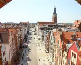 Widok na ulicę w **starym mieście Elbląg** z ceglanego muru. W oddali widać wieżę kościoła.
