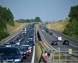 Korek samochodów na autostradzie A1, zieleń po bokach, błękitne niebo.