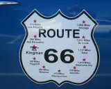 Tablica z napisem "ROUTE 66" i odległościami do miast, w tym "You Are Here Kingman".