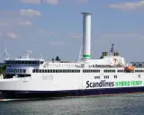 Prom na trasie Rostock-Gedser, "Berlin", z charakterystycznym, wysokim kominem i zielonym napisem "Scandlines HYBRID FERRY", płynie po wodzie.