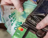 Dłonie trzymające portfel z banknotami euro. Od 2015 roku jaka waluta jest na Litwie? Euro.