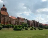 Zabytkowe miasto na trasie Ostróda-Grudziądz z ceglanymi budynkami i wieżą kościelną, otoczone zielenią i parkiem.