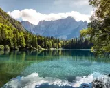 Krystalicznie czyste jezioro w regionie Friuli-Wenecja Julijska, otoczone lasem i majestatycznymi górami.