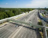 Szerokie drogi w Rosji z zielonym, przeszklonym mostem dla pieszych. Ruch samochodowy na wielopasmowej autostradzie.