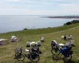 Ustronie Morskie trasa rowerowa z widokiem na morze. Dwa rowery turystyczne zaparkowane obok stolików i leżaków na trawie.
