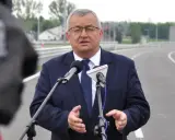 Mężczyzna w garniturze przemawia do mikrofonów na tle nowej drogi, która połączy Lublin i Rzeszów.