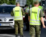 Policjanci w kamizelkach odblaskowych kierują ruchem podczas przejazdu przez Słowację. Kierowca w masce zatrzymuje się do kontroli.