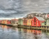 Kolorowe domy na palach wzdłuż rzeki, przypominające malownicze trondheim fiordy.