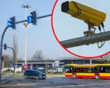 Żółte kamery na skrzyżowaniach rejestrują wykroczenia. Na zdjęciu widać skrzyżowanie z sygnalizacją świetlną, samochody i autobus.