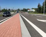 Nowy chodnik i droga rowerowa w mieście na trasie Gostyń-Kórnik. Czarny samochód jedzie po jezdni.