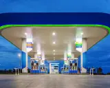 Stacja paliw z podświetlanym zadaszeniem i dystrybutorami. Widoczne ceny paliw, np. Diesel B10, Gasohol 95, E20.