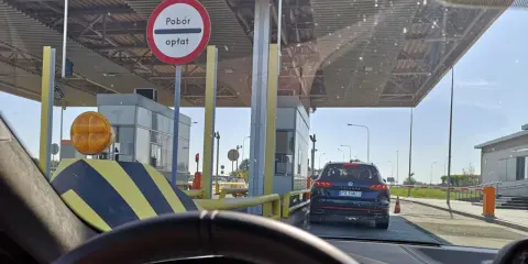 Kolejka samochodów do punktów poboru opłat. Znak informuje o poborze opłat.