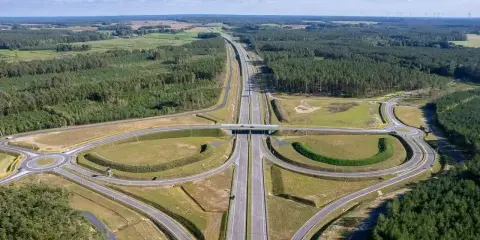 Węzeł drogowy na trasie Poznań-Kołobrzeg. Nowoczesna infrastruktura drogowa otoczona lasami i polami.