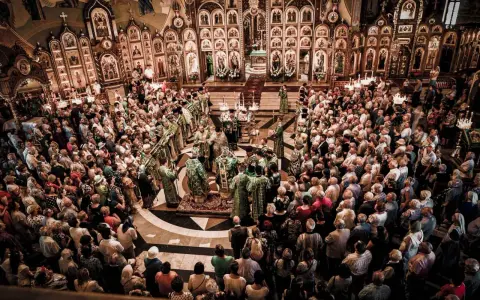 Uroczysta liturgia w największej cerkwi w Polsce. Wierni zgromadzeni wokół ikonostasu, duchowieństwo w bogatych szatach.